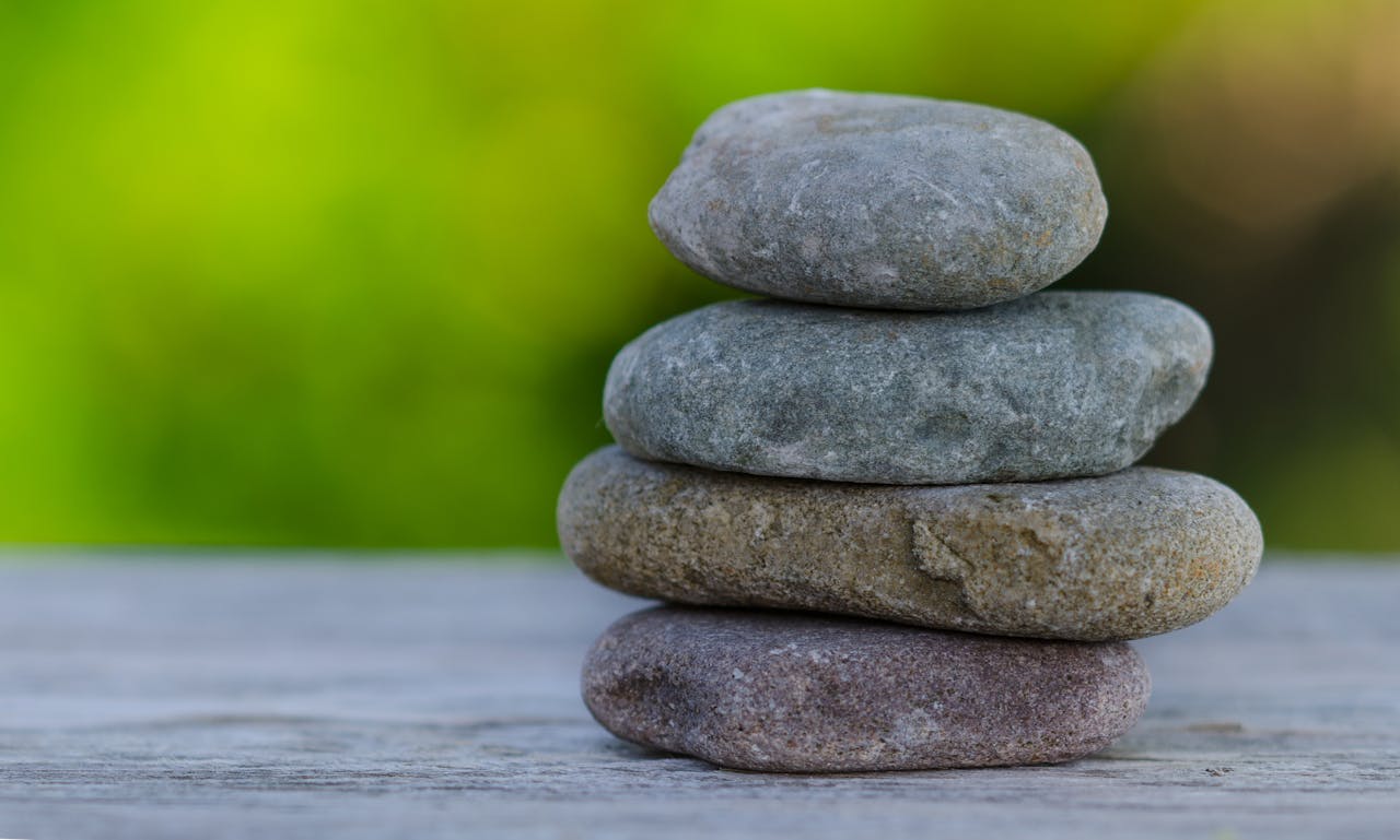 Four smooth stones stacked outdoors, symbolizing balance and tranquility.